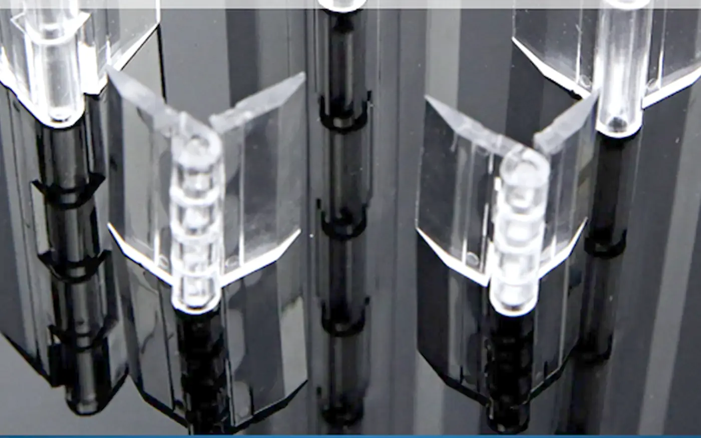 Clear acrylic hinges with an integral pin, photographed on a dark surface