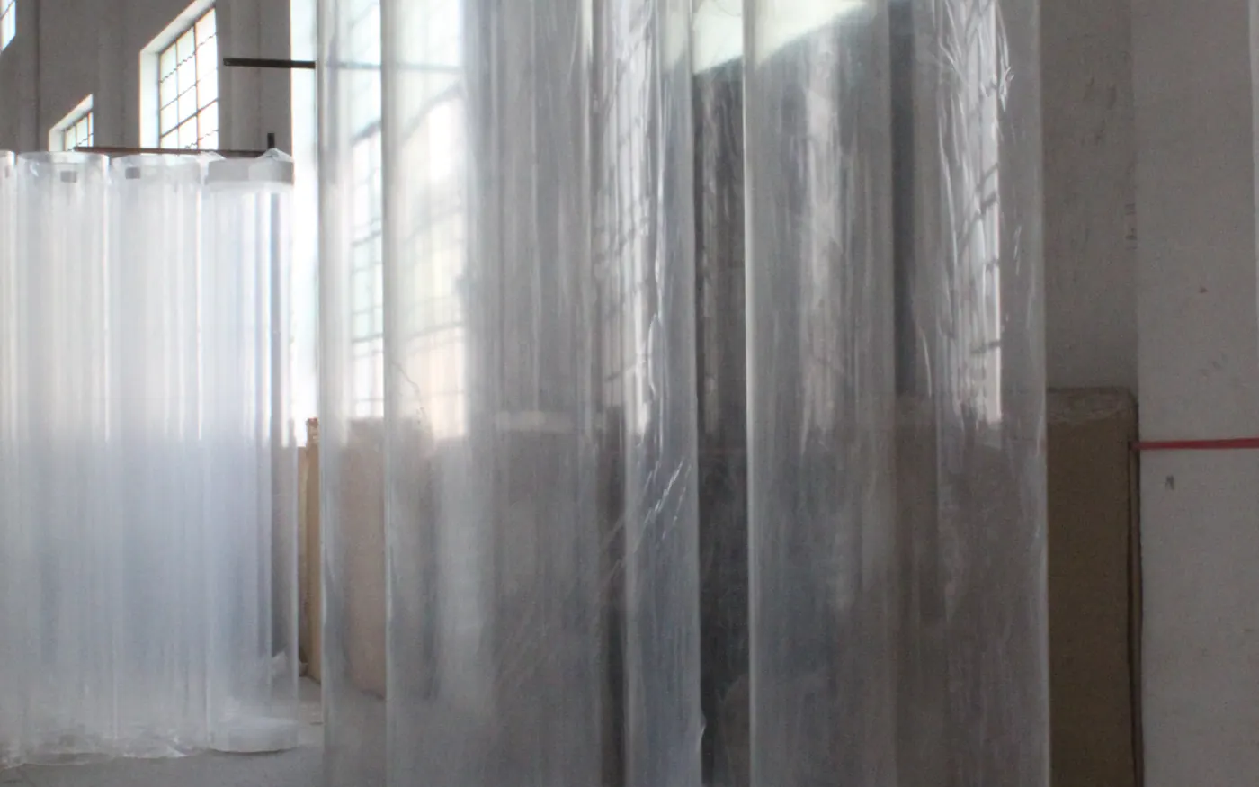 Large-diameter cast acrylic cylinders standing wrapped in the warehouse