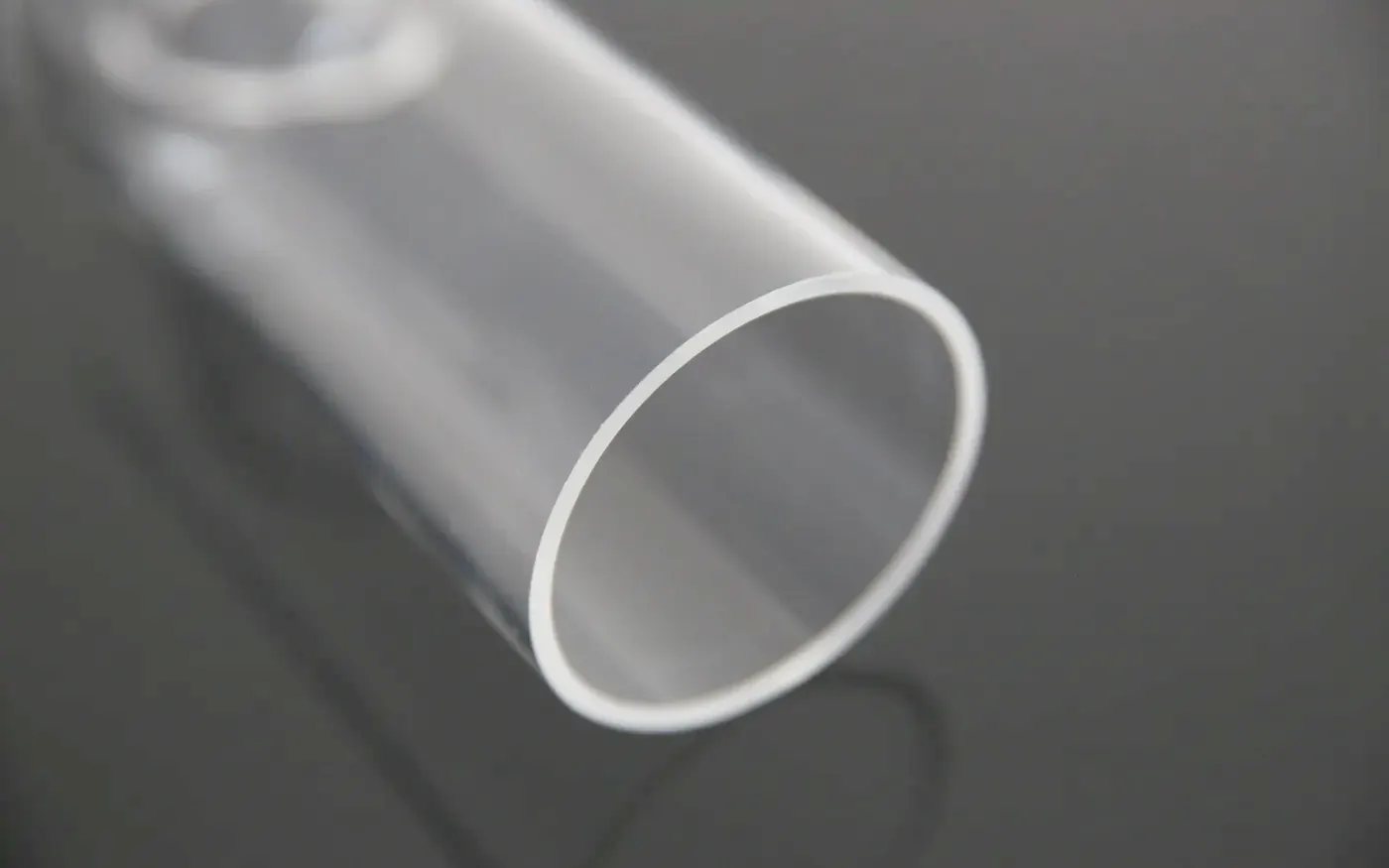 Clear extruded acrylic tube photographed end-on against a dark background