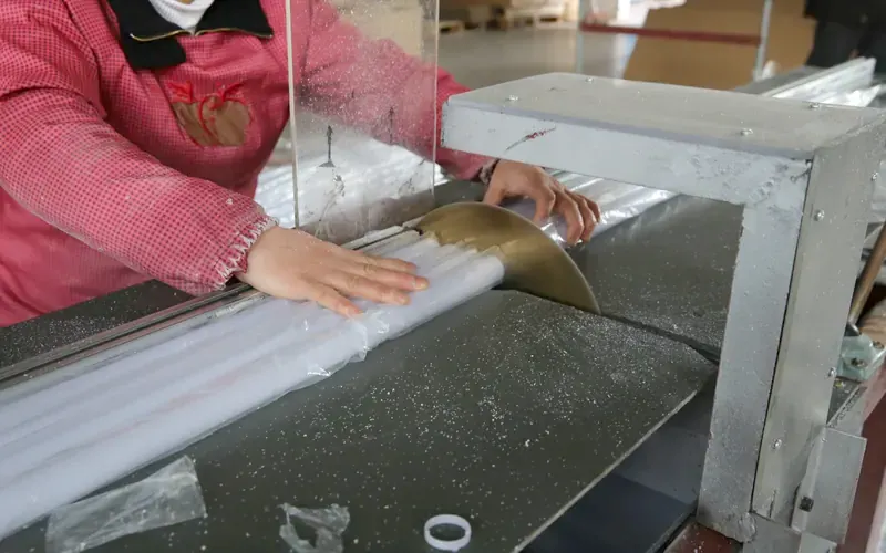 Operator cutting an acrylic tube to length on a saw