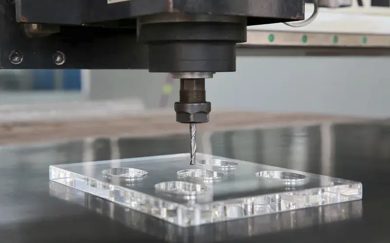 CNC machine drilling holes in a clear acrylic block